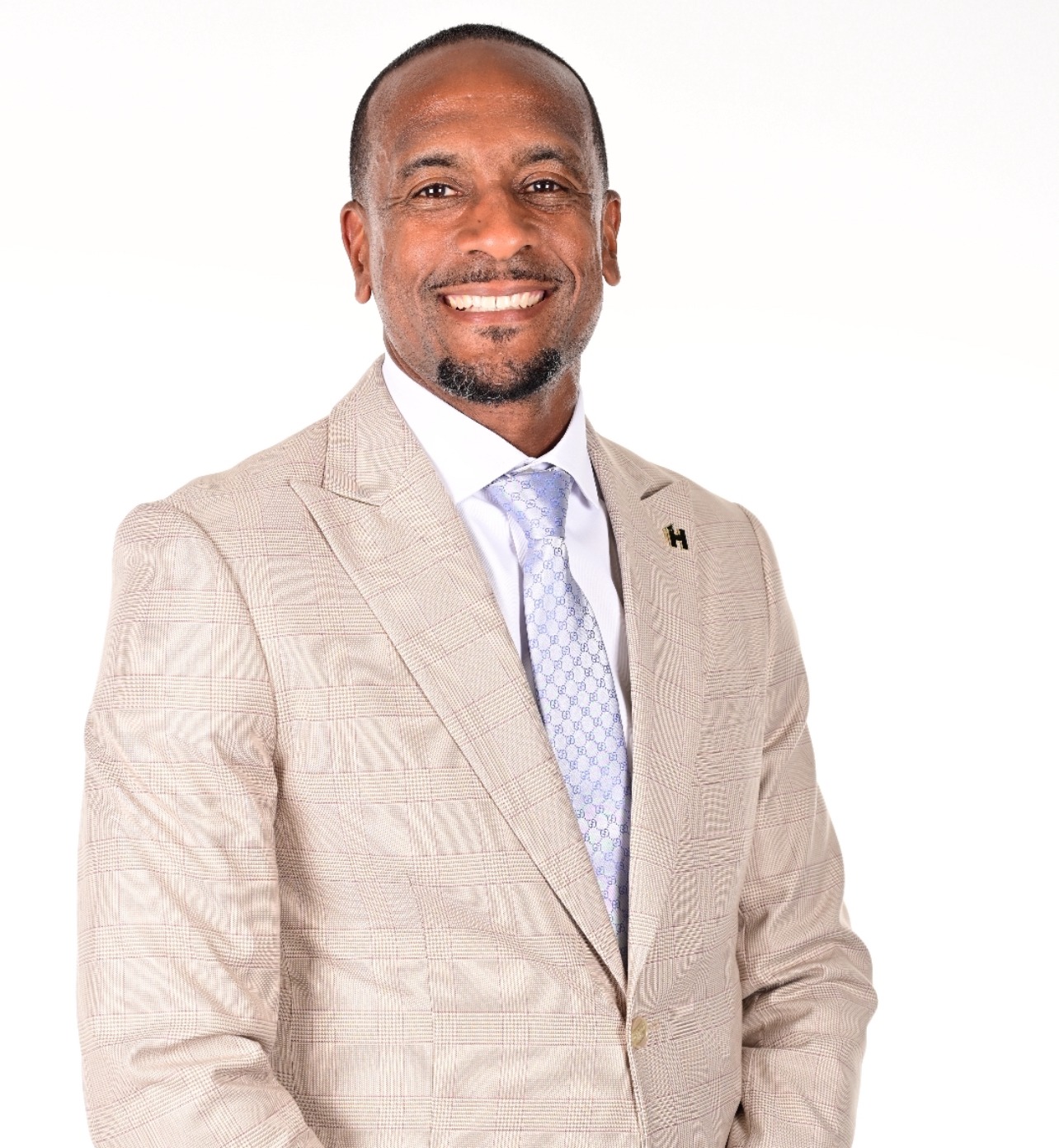 Smiling man in a light-colored suit and tie, posing against a white background