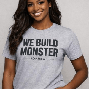Smiling woman wearing a gray t-shirt with "WE BUILD MONSTER" and "IDAREU" printed on it