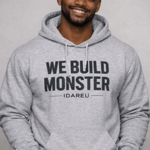 Smiling man wearing a gray hoodie with "WE BUILD MONSTER" printed on it