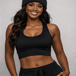 A smiling woman wearing a black crop top and sweatpants