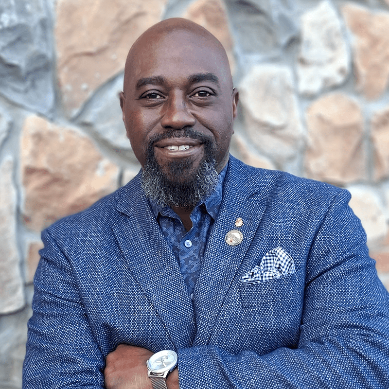 Confident man in a blue blazer stands with arms crossed